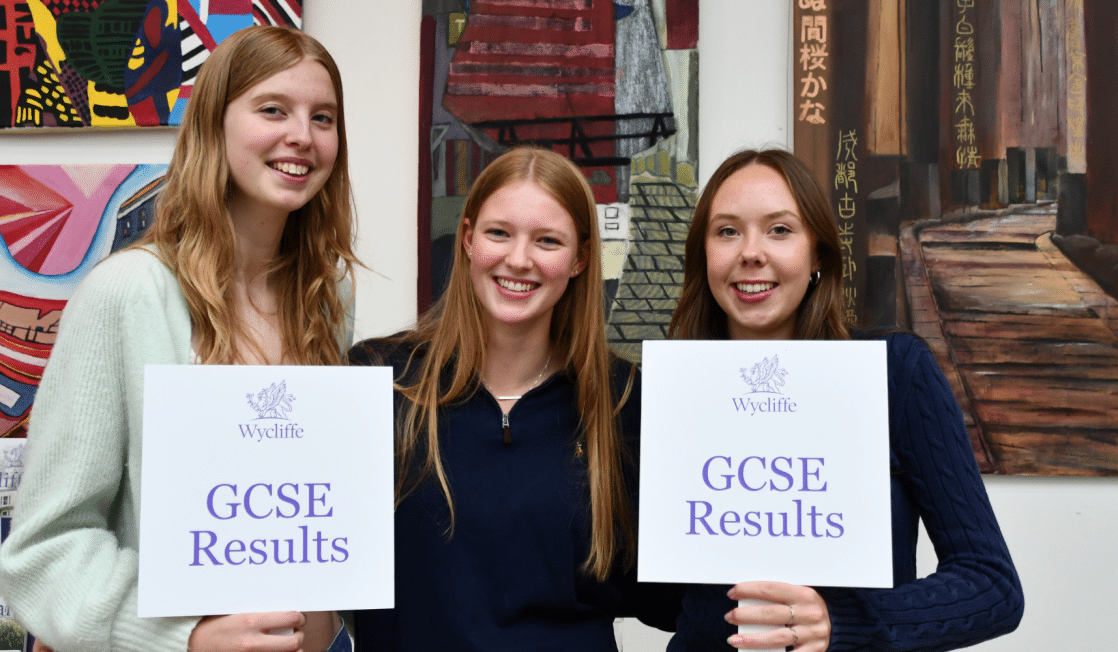 Three senior school girls holding GCSE signs