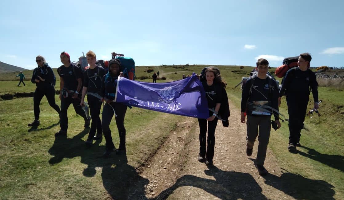 Group of school children on outdoor excursion, holding large Wycliffe banner flag