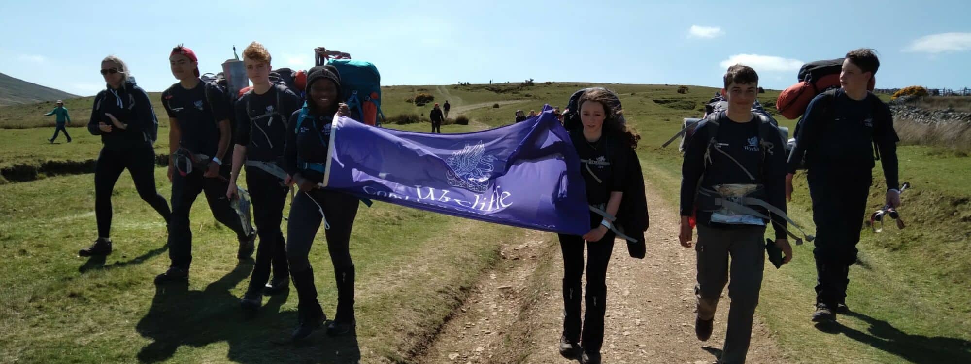 Group of school children on excursion holding large purple Wycliffe banner