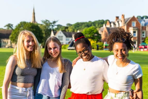 Group of school girls with arms around each other on playing field