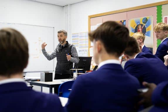 School pupils sat a desks listening to teacher