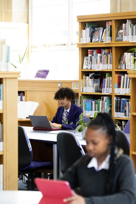 Senior school pupils working on laptops in library