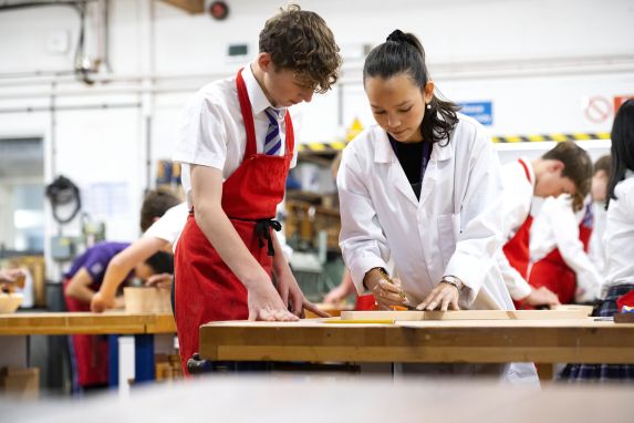 Girl and boy pupil wearing protective clothing working together