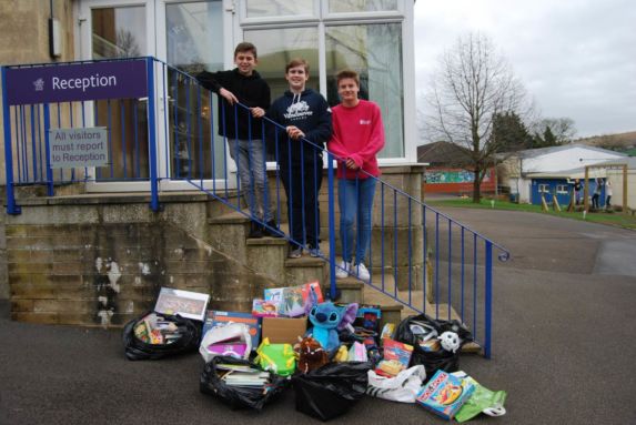 Three school pupils standing on steps next to collection