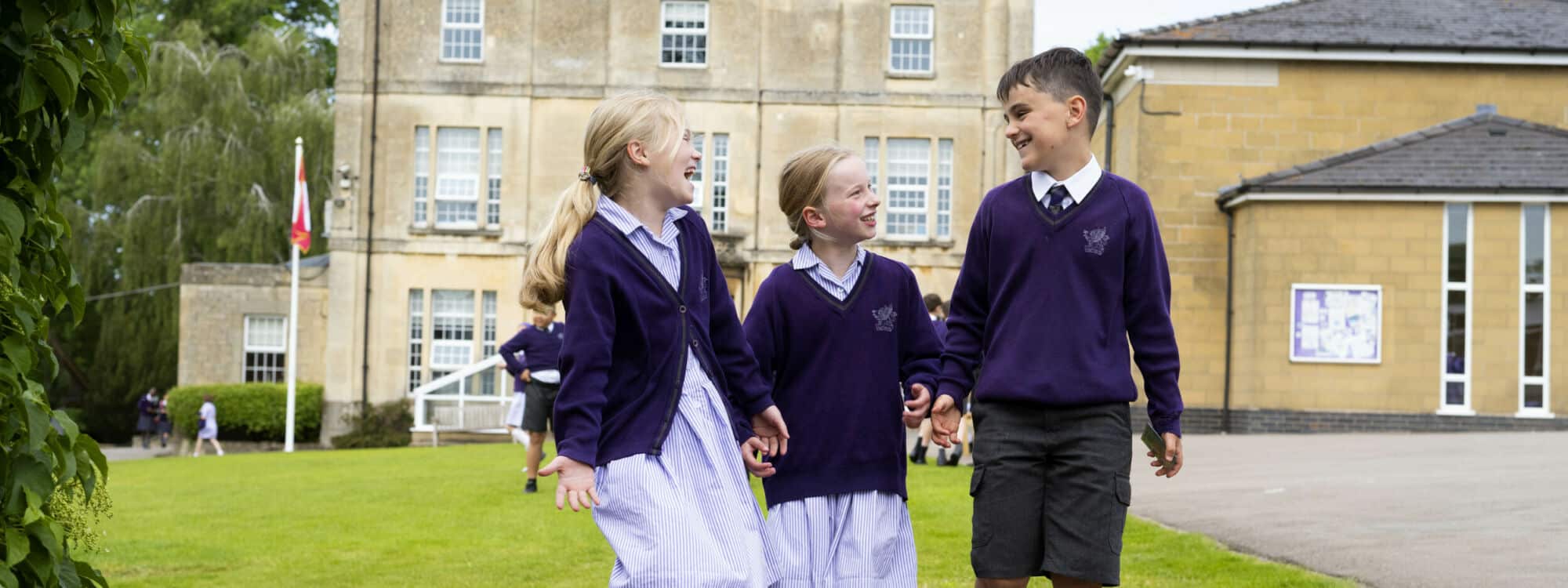 Two girl and one boy school pupil holding hands in outdoor space