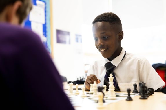 School boy of black ethnicity playing chess