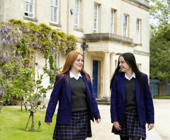 Two girls walking with building in background