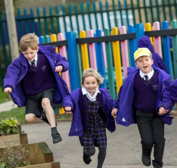 Nursery and pre prep girl running with two older boys either side