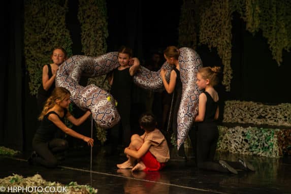 Prep school theatrical performance holding giant crafted snake