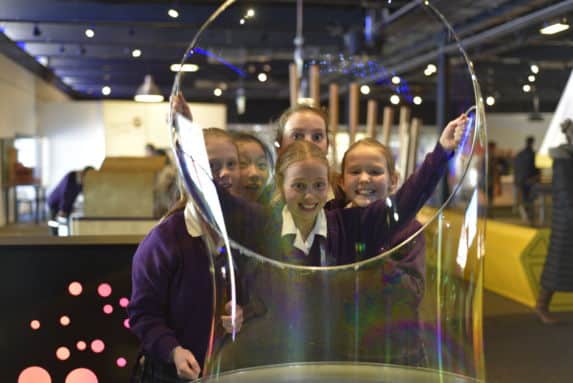 Prep school girls at science centre with giant bubble hoop