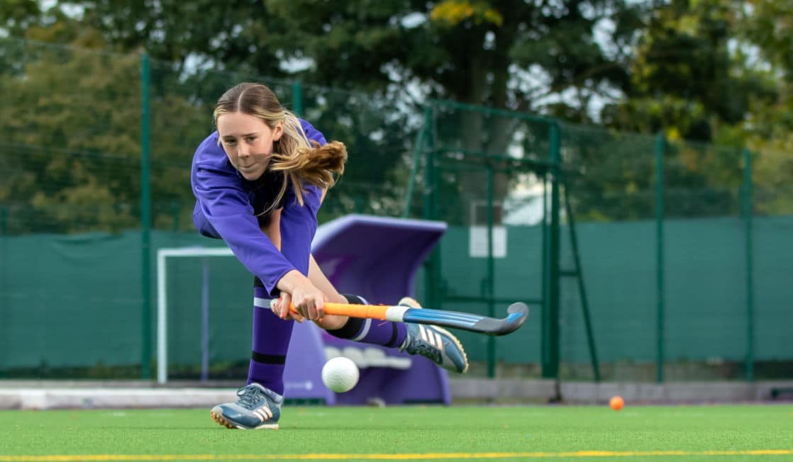 Senior school girl hitting hockey ball