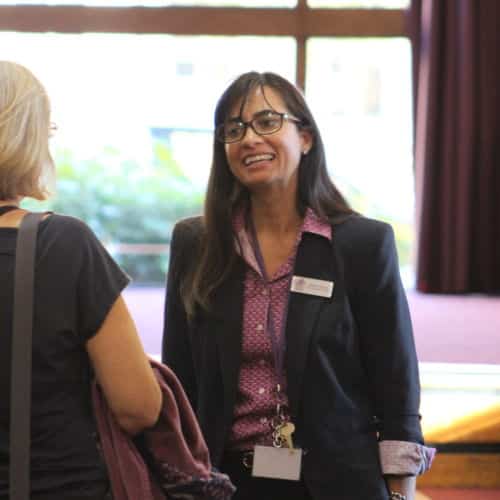 Female teacher smiling, speaking with school pupil